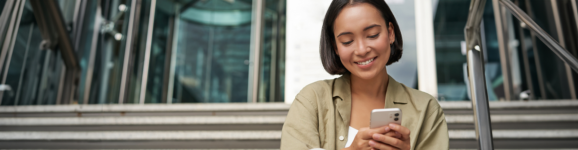 Mulher sorrindo usando celular em ambiente corporativo